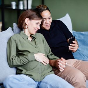 Pregnant woman looking at a mobile phone with her partner 