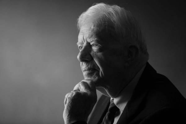 President Jimmy Carter rests his chin on his hands looking forward.