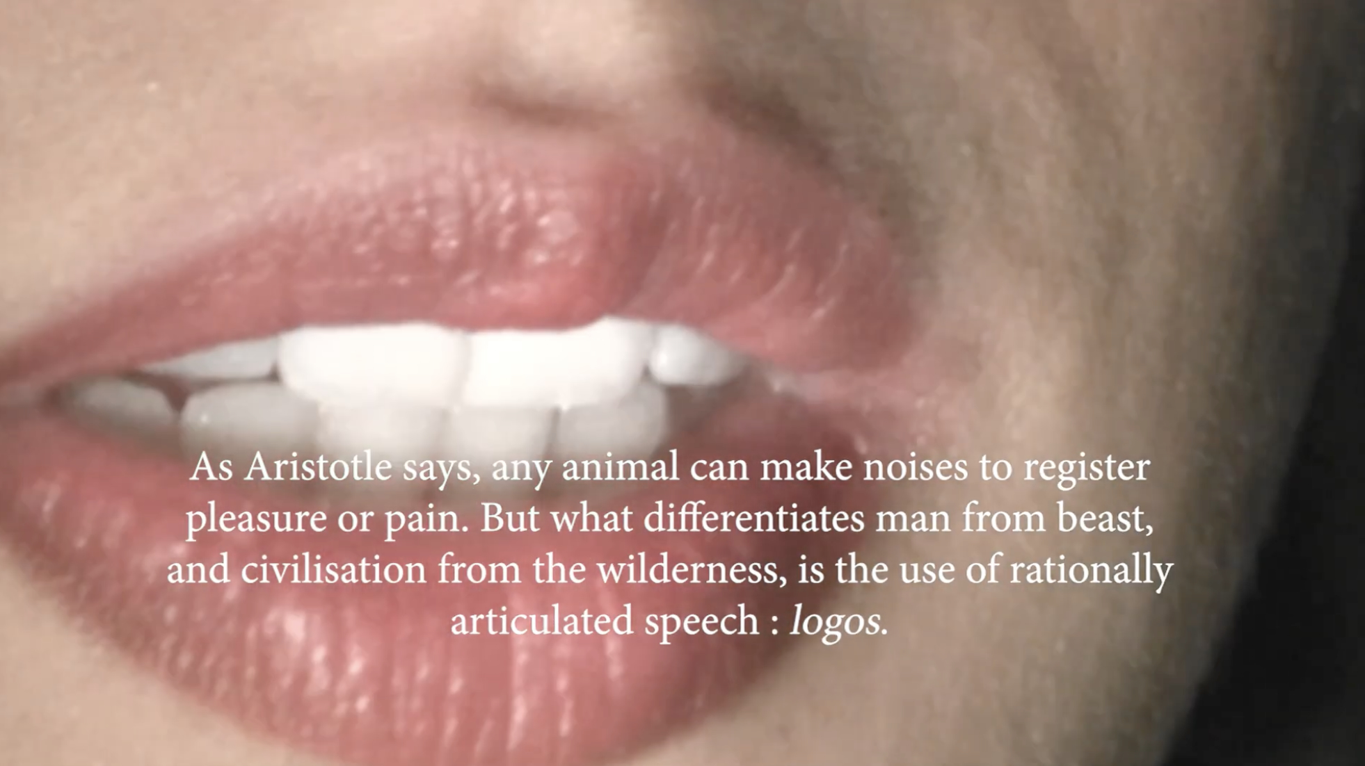 A screenshot of a 12:18 video which alternates between shots of mouths speaking and footage from popular culture films and television. The screenshot shows an opened mouth that is overlayed with white text saying "As Aristotle says, any animal can make noises to register pleasure or pain. But what differentiates man from beast, and civilisation from the wilderness, is the use of rationally articulated speech : logos."