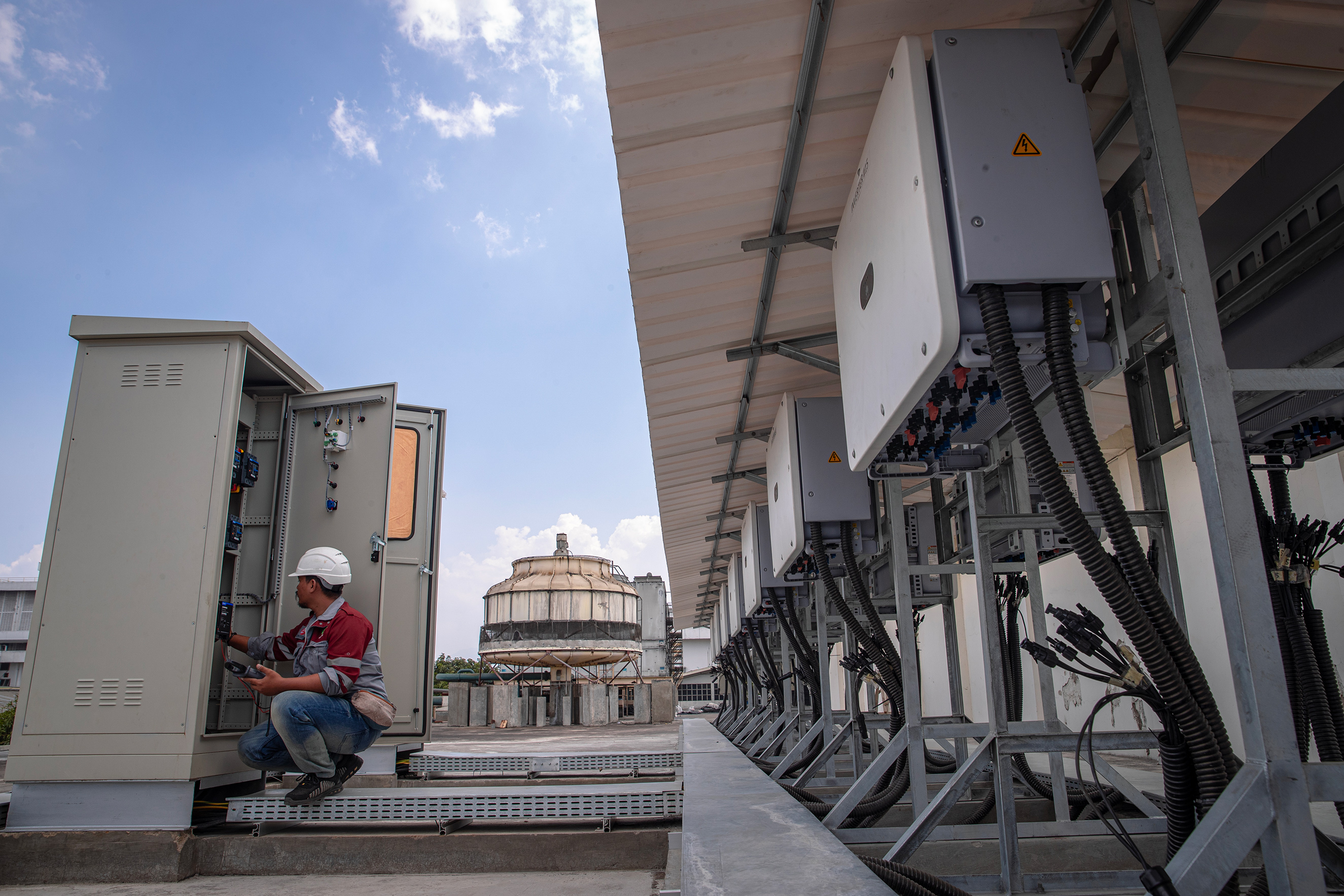 Seorang petugas memeriksa keberadaan sistem pemasangan panel surya dari inverter di atap gedung pabrik di Rankekek, Bandung.