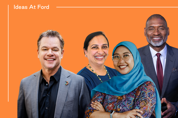 Four individuals, two men and two women, dressed in business casual and formal attire, stand against an orange background with "Ideas At Ford" written in white at the top left. The women are smiling; one wears a hijab. The men are also smiling, with one in a suit and tie.