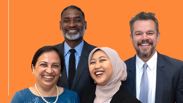 Four individuals, two men and two women, dressed in business casual and formal attire, stand against an orange background with "Ideas At Ford" written in white at the top left. The women are smiling; one wears a hijab. The men are also smiling, both in a suit and tie.