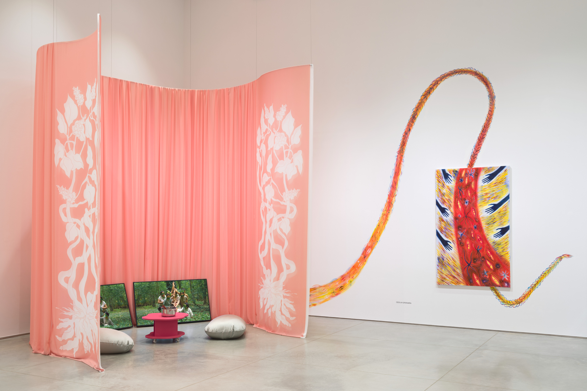 Gallery corner with a semicircular video installation surrounded by a pink curtain. And to the right, an abstract wall painting resembling a partially braided band of fire.