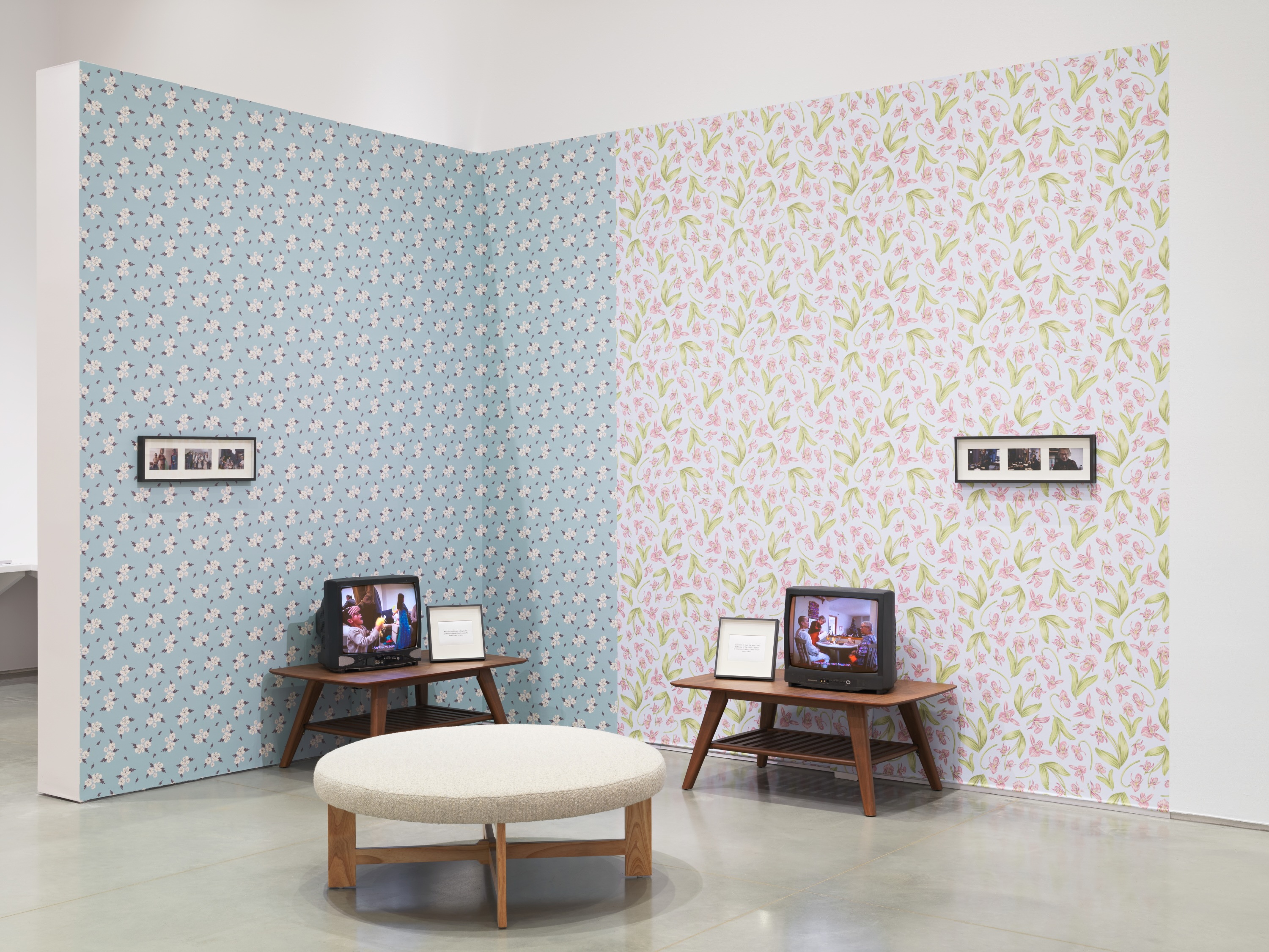 Corner installation with two vintage television sets against floral wallpaper.