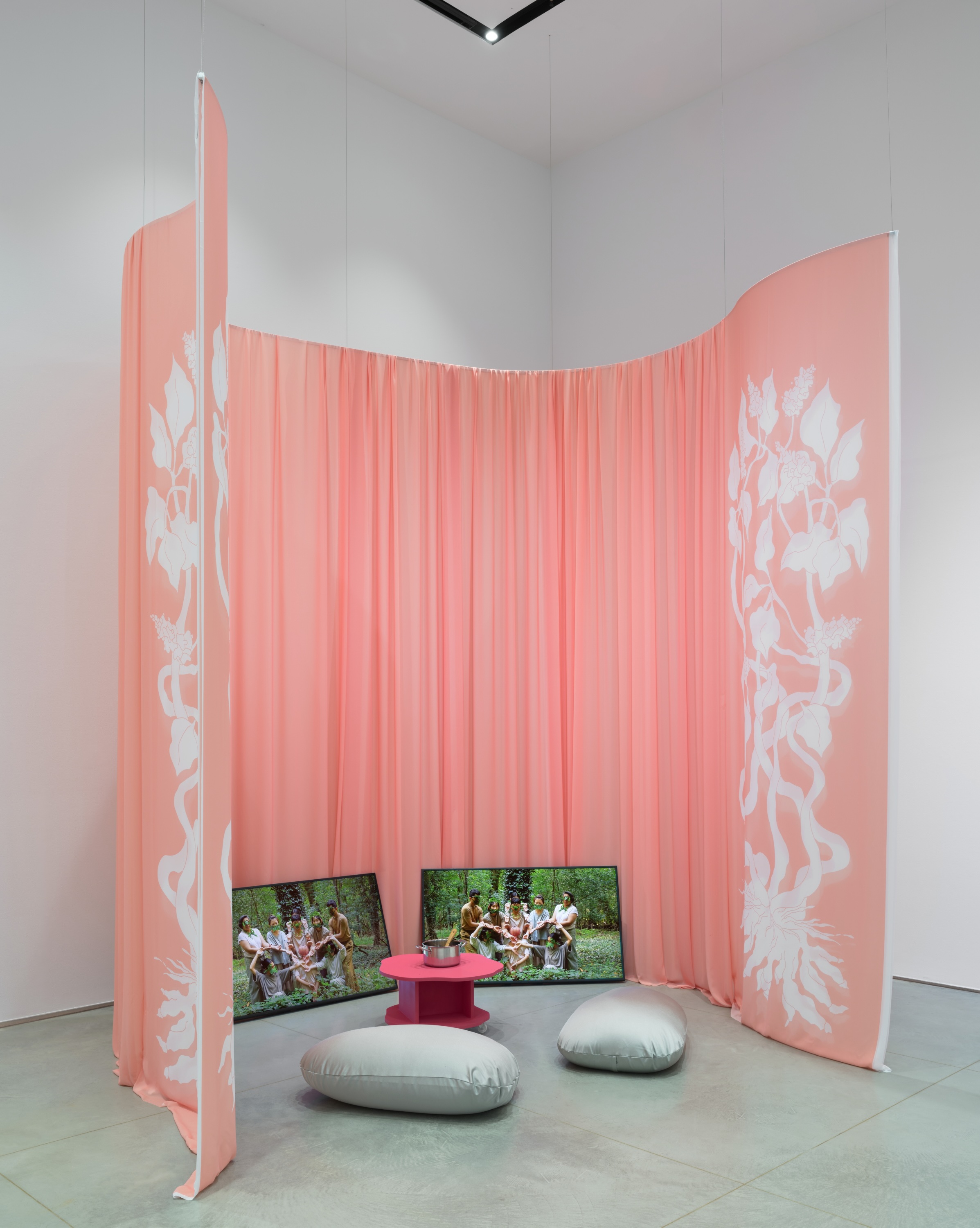 Semicircular video installation surrounded by a pink curtain.