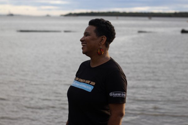 Ana Bolena Rodríguez is standing in a lake wearing a dark blue t-shirt with white text on it.