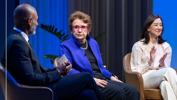 Three people are sitting in conversation against a blue curtain background. The group includes, from left to right, Charles Blow in a dark suit, Billie Jean King in black with a blue blazer, and Clara Wu Tsai in a beige white and trousers.