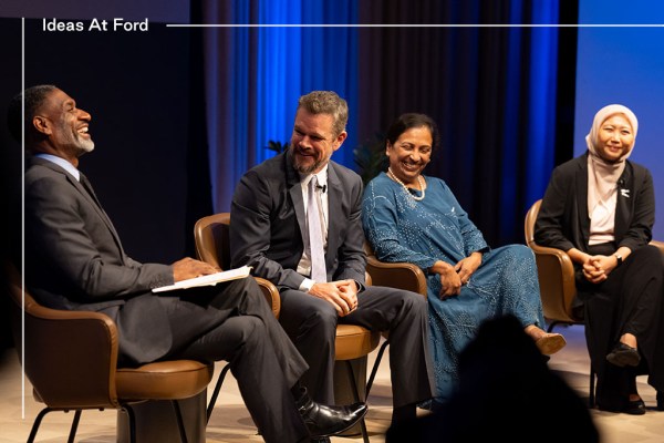 Four individuals, two men and two women, dressed in business casual and formal attire, are sitting in conversation against a blue curtain background. The women are smiling; one wears a hijab. The men are also smiling, both in suits and ties. From left to right, they are Charles Blow, Matt Damon, Vedika Bhandarkar, and Kiki Tazkiyah.