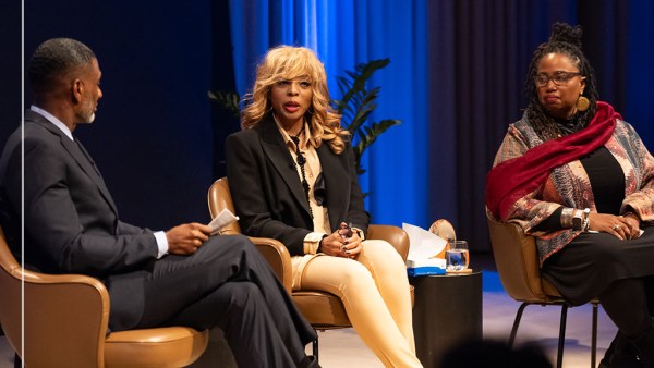 Three people are sitting in conversation against a blue curtain background: from left to right they are Charles Blow in a dark suit and tie, Stephanie “Sparkle” Edwards, in a black blazer and beige top and slacks and Aishah Shahidah Simmons in a patterned jacket, black top and slacks and a maroon scarf.